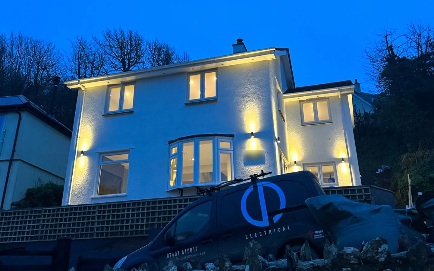 A South Devon house at dusk with new outdoor wall lights, and the CD Electrical van outside